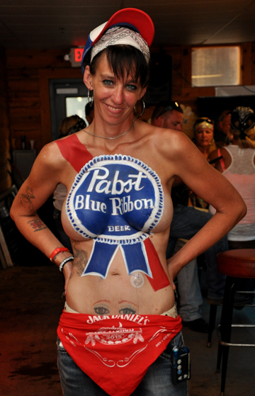 body painted black haired woman with a detailed pabst blue ribbon logo on her chest